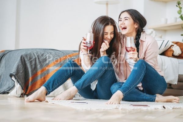 young carefree laughing brunette girls friends in casual with glasses of wine having fun together on t20 jrdzpp