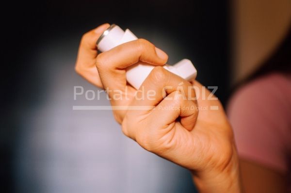 a close up view of a young woman using an asthma inhaler device indoor t20 6mpjgy