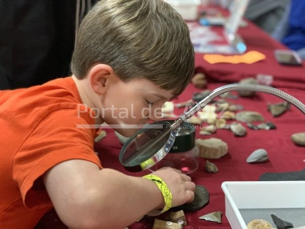 little boy looking at fossils through a magnifying glass at a rock and gem show childhood excitement t20 vlone6