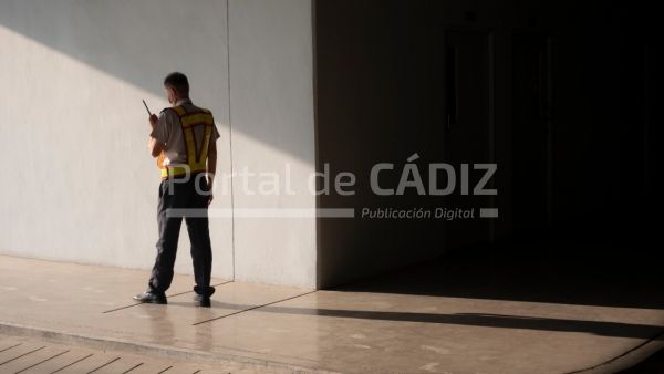 asian security guard in safety vest walking on sidewalk of parking garage he using walkie talkie or t20 a9lnp1