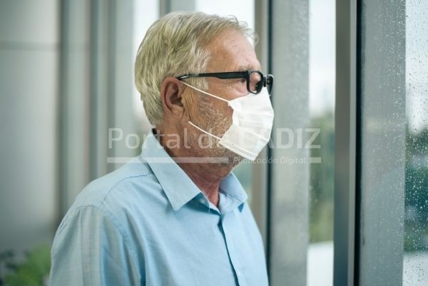 old caucasian man is wearing medical mask looking to outside his home sick medical mask lockdown t20 er8m7v